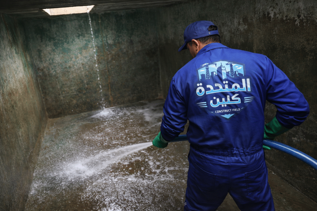 شركة تنظيف خزانات بظهران الجنوب عامل يقوم بتنظيف خزان أرضي بالمياه باستخدام معدات متخصصة لإزالة الرواسب والأوساخ